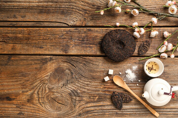 Dry pressed puer tea with teapot, cup, sugar cubes and cherry blossom on wooden background