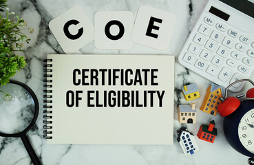 COE Certificate of Eligibility text written on notepad with house model, calculator, magnifying...