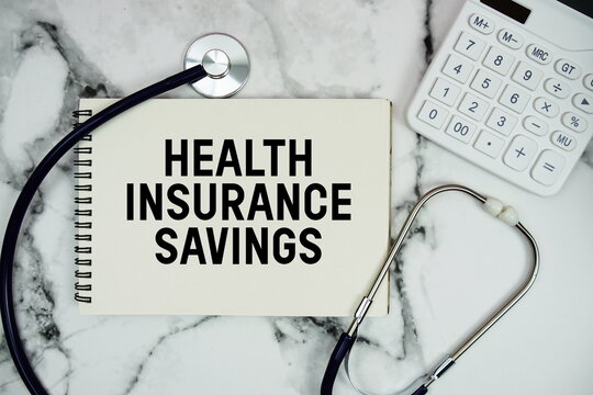 Health Insurance Savings text written on notepad with stethoscope and calculator on marble background