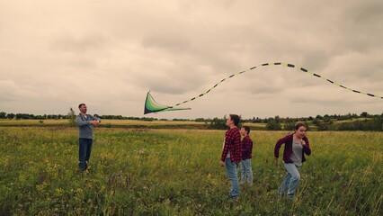 Dad flying kite with two kids, children dreaming of touching the sky, outdoor playtime filled with giggles, father teaching and guiding, brother and sister chase dreams, green field adventure, sky