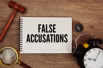 False Accusations message written on notepad with alarm clock, wood gavel and magnifying glass flat...