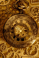 Gold antique pocket fob watch with gears and cogs in the background. Vintage industrial steampunk fashion accessories.