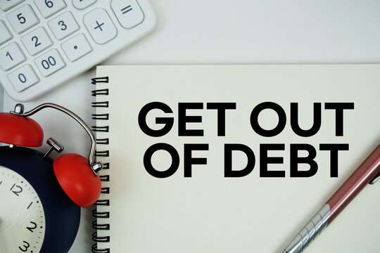 Get Out of Debt text written on notepad with alarm clock and calculator on white background