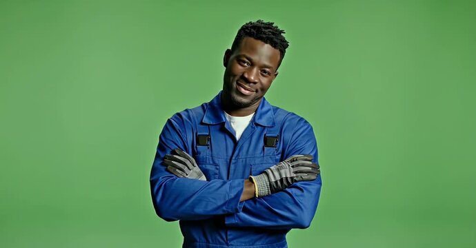 Confident African American mechanic in blue overalls with arms crossed.