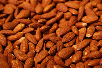 Delicious roasted almonds with spices are sold in large quantities at a vegetable market. Close-up. Almond background.