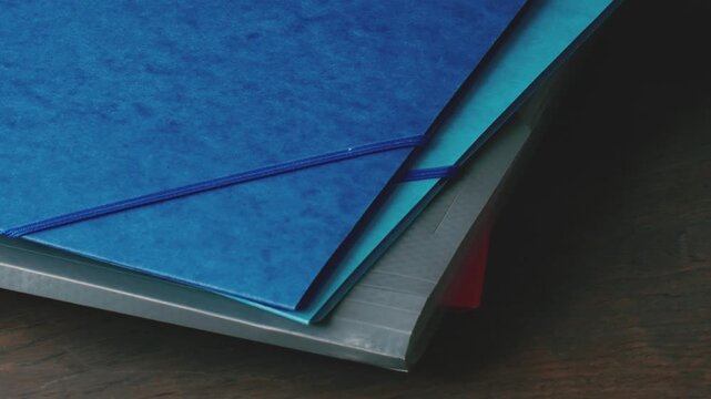 Close look at office supplies and folders in a stack organized on a desk; sorting important documents for work or school