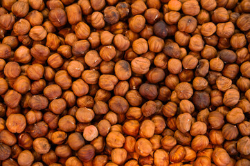Shelled hazelnuts lie in a pile as a background. Dried and ready-to-eat hazelnuts. The texture of an orange hazelnut