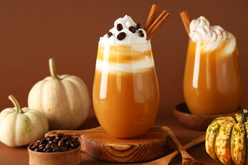Glasses of orange pumpkin spice latte on brown background, closeup