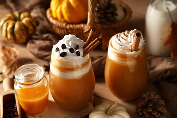 Glasses of orange pumpkin spice latte on wooden table, closeup