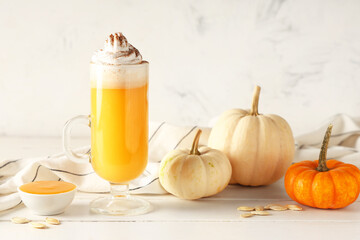 Glass of orange pumpkin spice latte on white wooden table
