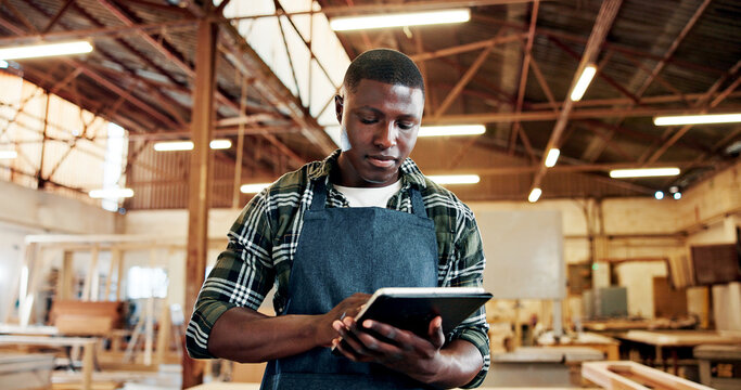 Carpenter, serious and man with tablet, workshop and plan for furniture production on web or online. Small business, artisan and black person with tech for inventory, manufacturing and craftsmanship