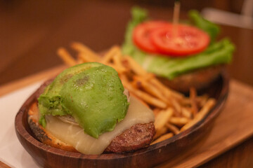 Avocado hamburger served with potato chips on plate. Selective focus, blurred background