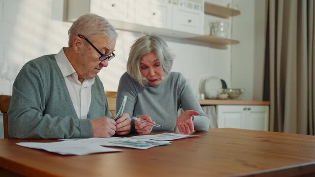 Lack of money and finance problem of old married couple, spouses planning budget . Senior woman and her husband counting cash dollars, spending money for utility bills and mandatory payments, economy