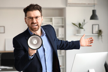 Angry businessman shouting into megaphone in office