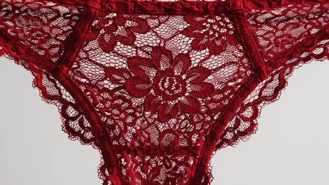 A person holding a pair of delicate red lace thong panties.