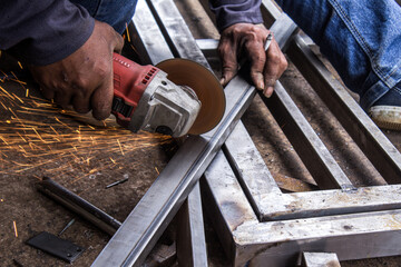 Metal Worker Using Angle Grinder Cutting Steel with Flying Sparks