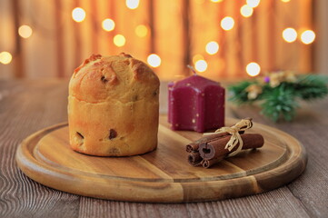 Closeup of Christmas bread, candle and cinnamon with Christmas lights in background
