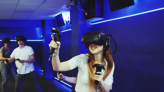Young woman with handheld controllers in hands clearly excited and engaged in virtual world experiencing through VR glasses covering face. Concept of immersion and interactivity in game