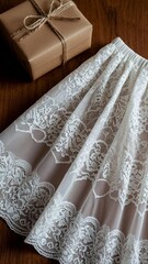 White lace skirt with intricate floral patterns and elastic waistband displayed on wooden surface next to a brown gift box tied with twine