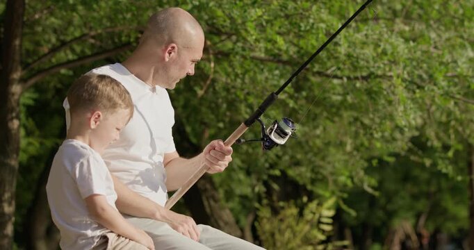 Irritated father scolds small son for handling fishing rod carelessly. Bold man explains correct way to release line. Dad tells preschooler child to focus on task
