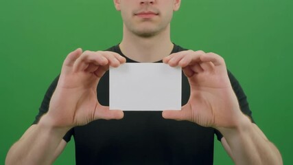 Man holding blank white card against green background