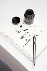 Calligraphy training. A close-up top view of a pen and ink bottle, creative attempts, and the...