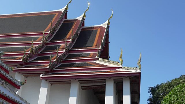 Wat Pho temple rooftops in Bangkok, Thailand, showing traditional Thai architecture details and golden chofas under a clear blue sky, highlighting a prominent cultural landmark