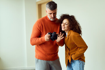 Couple Photographers Review Camera Together in Modern Workspace, Smiling and Learning New Techniques