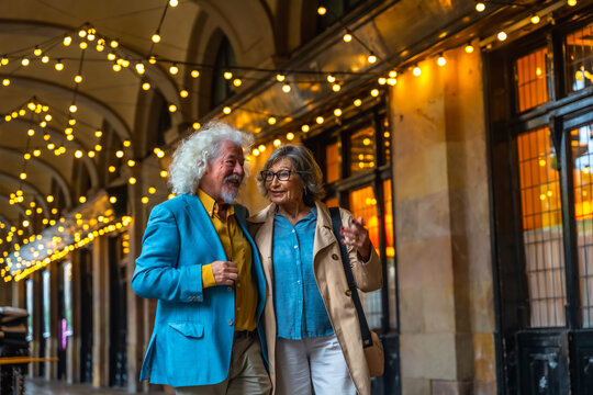 Senior couple enjoying conversation walking city street at night - Powered by Adobe