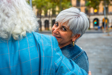 Senior woman smiling embracing partner in city