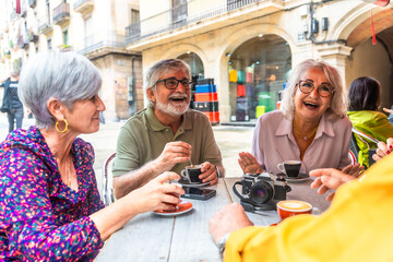 Group of senior friends enjoying coffee time laughing outdoors