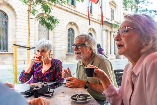 Senior friends enjoying coffee and conversation at outdoor cafe