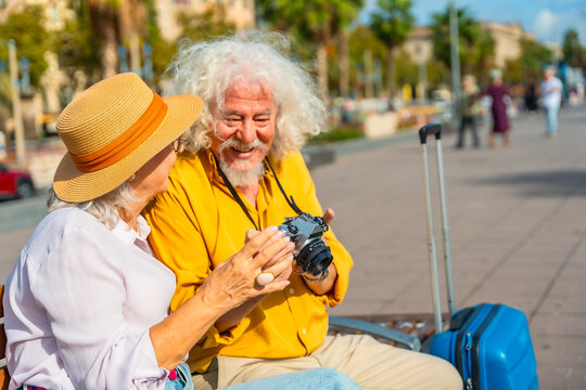 Senior couple traveling together examining camera on vacation - Powered by Adobe