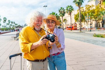 Senior couple traveling smiling looking at vintage camera