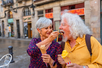 Senior couple sharing ice cream in city street
