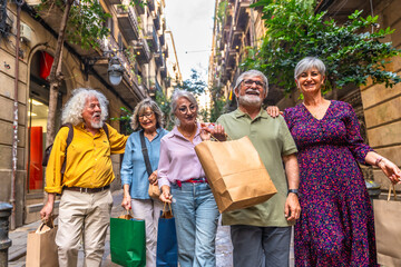 Happy senior friends enjoying shopping together on city street
