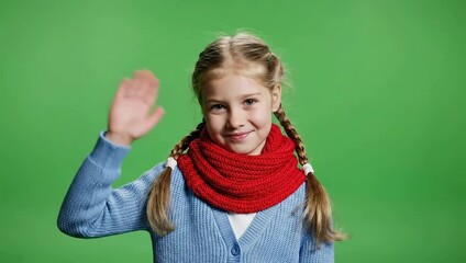 Cute little girl waving hello and goodbye on green screen.