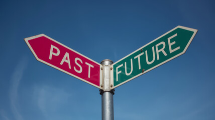 Obraz premium A fork in the road sign one arrow points to PAST in pink the other to FUTURE in green against a blue sky.