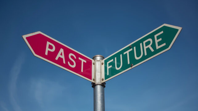 A fork in the road sign one arrow points to PAST in pink the other to FUTURE in green against a blue sky.