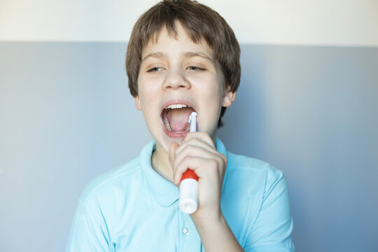 Young boy enjoys brushing teeth with a colorful toothbrush in a bright bathroom