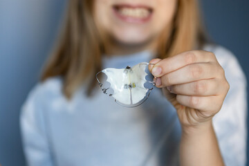 Child showing dental retainer with a smile in a well-lit indoor setting during the day