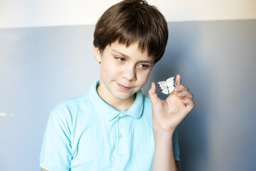 Boy smiles while holding a small piece of paper with a shape in a blue and white room