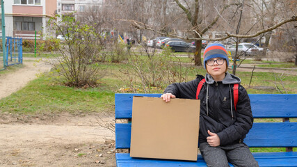 boy in a hat sits on a blue bench with a large box