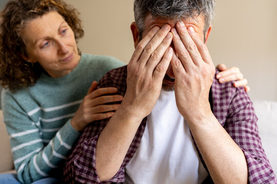 Woman comforting sad man covering face with hands