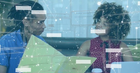 Reviewing colleagues in blue shirt and red blouse in booth with green folder, laptop and overlay