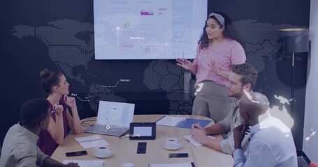 Presenting woman in pink top gesturing toward screen in conference room, laptops, copy space