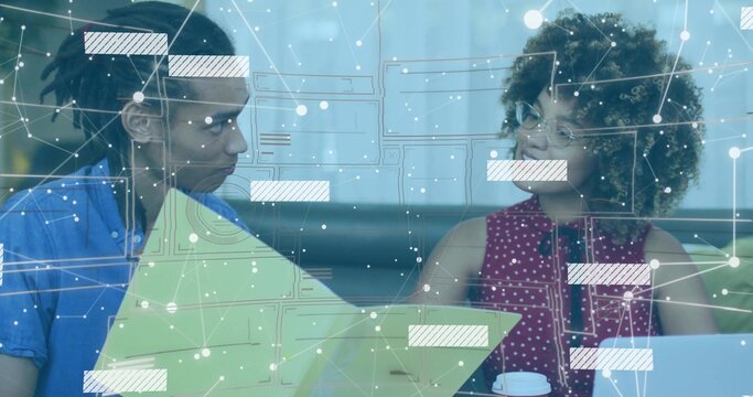 Reviewing colleagues in blue shirt and red blouse in booth with green folder, laptop and overlay - Powered by Adobe