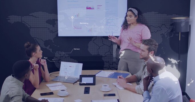 Presenting woman in pink top gesturing toward screen in conference room, laptops, copy space