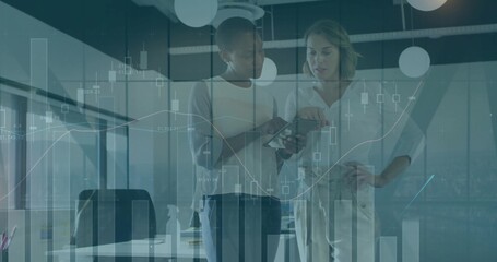 Viewing two colleagues examining tablet in office wearing business casual, showing financial charts
