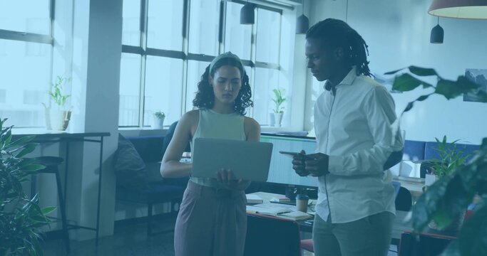 Reviewing, two colleagues in business casual holding laptop and pointing with stylus in open office - Powered by Adobe